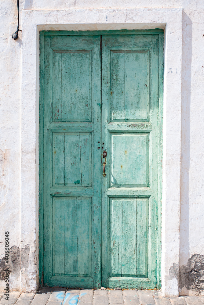 Green wooden door of a whitewashed house, typical of the town of Teguise, in Lanzarote