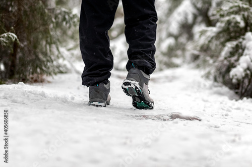 Male feet are walking along a snowy path in the forest. Close-up. Active lifestyle. Walk in the woods. Winter in the forest. Winter road.
