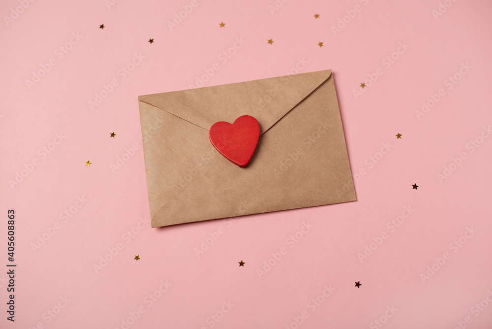 Craft envelope with the wooden heart and little golden stars on the rose background. Flat lay, top view. Romantic love letter for Valentine's day concept. Craft envelope with the wooden heart and little golden stars on the rose background. Flat lay, top view. Romantic love letter for Valentine's day concept.