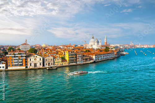 A Venice, Italy water taxi cruises the grand canal with the dome of Santa Maria Della Salute Cathedral, the Campanile and St. Mark's square in view photo