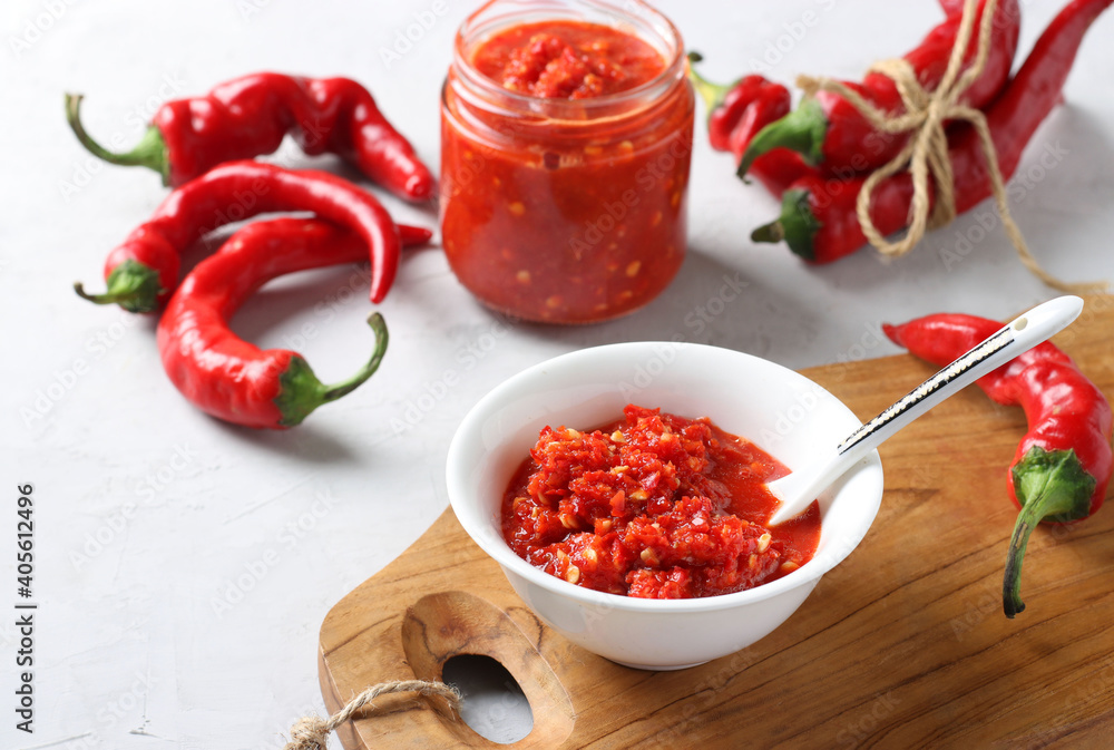 Traditional sauce adjika with hot chili pepper, paste harissa in bowl on wooden board. Closeup Traditional sauce adjika with hot chili pepper, paste harissa in bowl on wooden board. Closeup