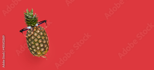 pineapple with glasses on a red background copy space