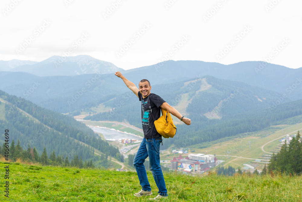 A guy travels with a yellow backpack through picturesque places with beautiful mountain landscapes