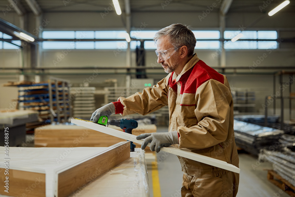 Carpenter measuring plank with tape measure in a workshop. Carpenter measuring plank with tape measure in a workshop.