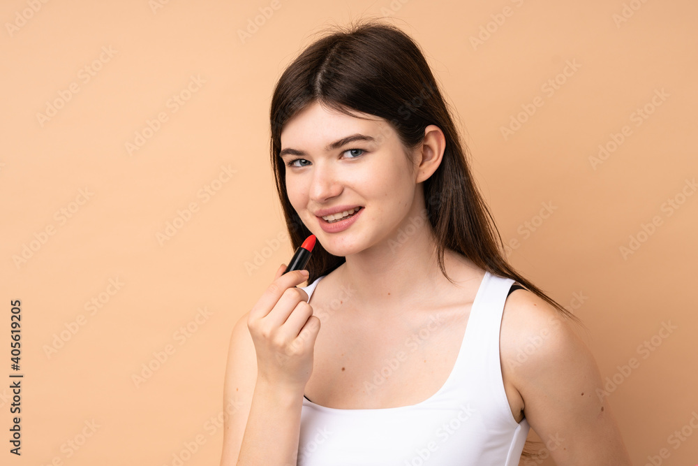 Young Ukrainian teenager girl over isolated background holding red lipstick Young Ukrainian teenager girl over isolated background holding red lipstick
