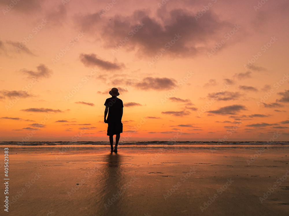 man walking on the beach in a sunset