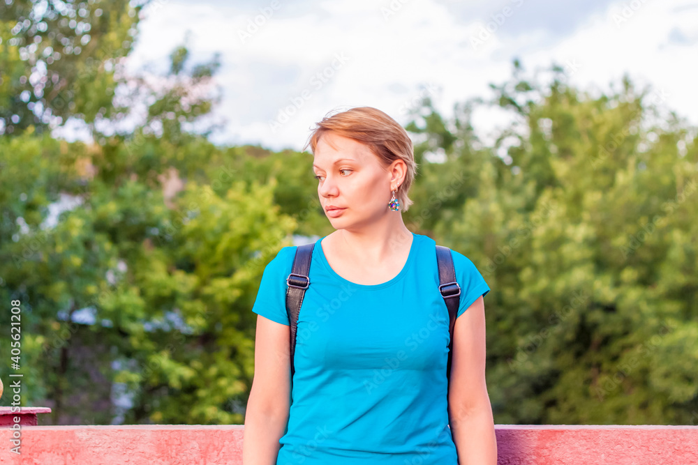 Portrait of a young girl. A girl in a blue T-shirt is standing on the street. The expression on his face.