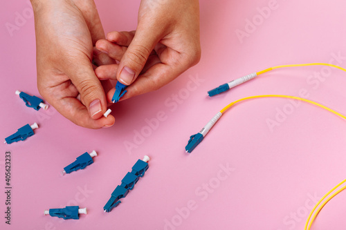 woman s hands hold LC connector fiber optic patch cord single mode on pink background
