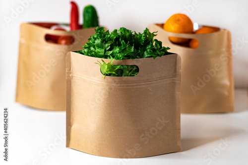 Reusable zippered paper bags for storing food with fresh vegetables, salad and fruits. Plastic-free packaging, zero west concept.