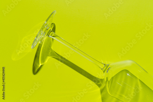 A part of champagne glass lies on light green surface. Glass with hard shadow 