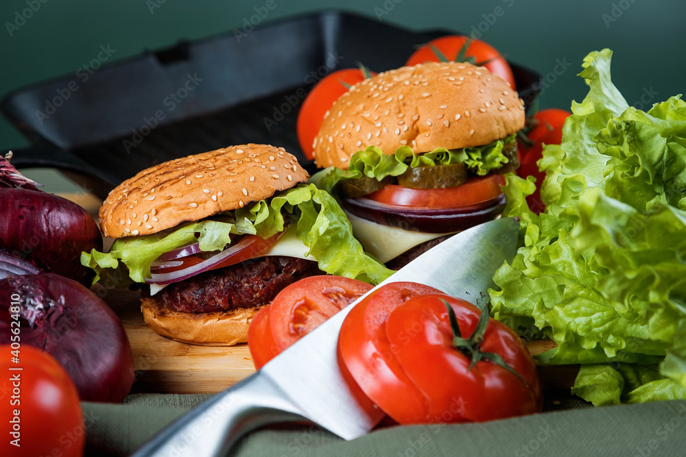 A delicious burger next to a fluted skillet. A chef's knife. Lots of vegetables. A delicious burger next to a fluted skillet. A chef's knife. Lots of vegetables.