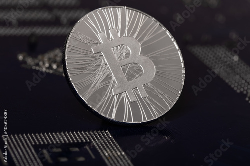 Crypto currency silvery coin with bitcoin symbol on background of an electronic microcircuit. Cryptocurrency Concept.