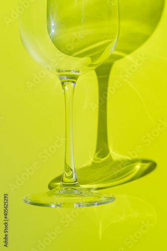 A part of wine glass lies on lemon green background. 