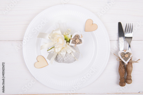 Romantic table setting with eco-friendly linen packaging gift with wooden heart decoration. Eco friendly zero waste present set for Valentines Day, Birthday or Mothers Day