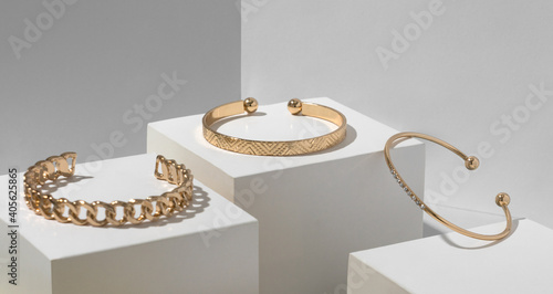 Three golden bracelets on white geometric paper cubes