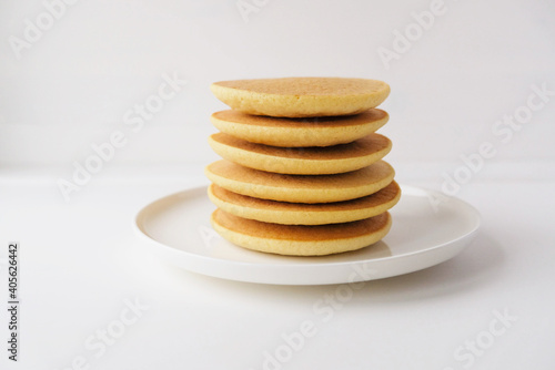 Freshly cooked soft delicious gluten free pancakes stacked on white plate, close up. Space for text. Healthy sweet food.