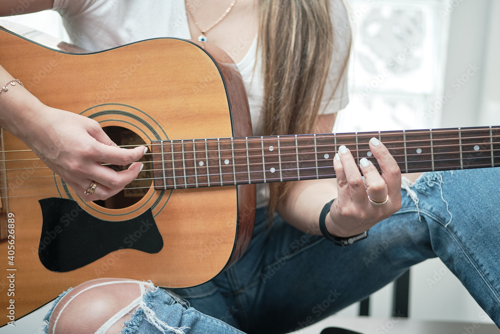 girl's hands playing an acoustic guitar