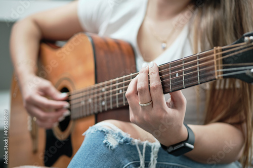 girl's hands playing an acoustic guitar