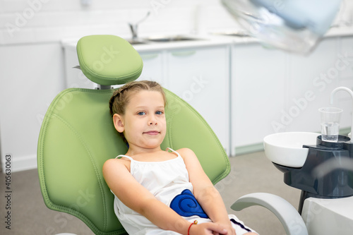 Little girl looks worried in a dental chair. Visiting dentist with children