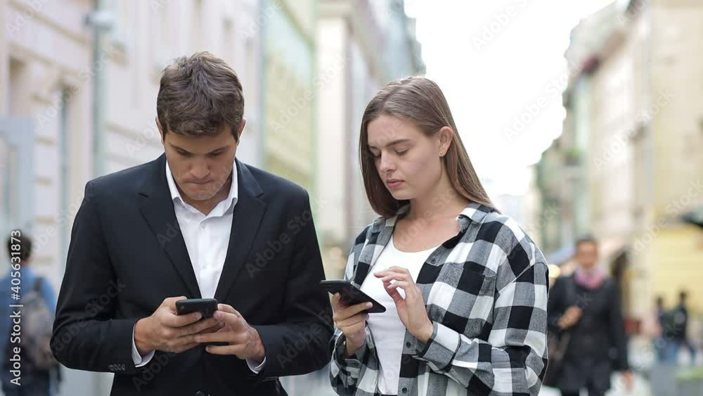 A young couple uses their phones on the street, it is important to correspond in bulk in social networks. A young couple uses their phones on the street, it is important to correspond in bulk in social networks.