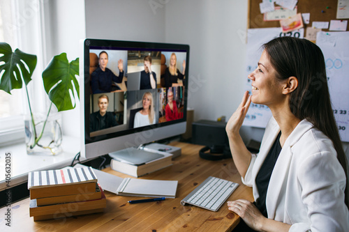 Young woman having Zoom video call via a computer in the home office. Stay at home and work from home concept during Coronavirus pandemic. photo