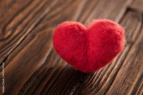 Valentine s day card with a backlit red woolen heart which is standing on the brown textured wooden boards. Copy space.