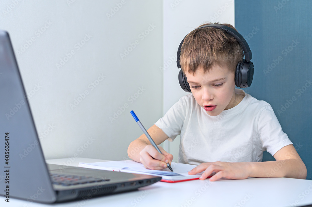 Schoolboy studying homework during her online lesson at home. Online education. Schoolboy studying homework during her online lesson at home. Online education.