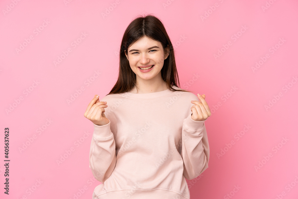 Young Ukrainian teenager girl over isolated pink background making money gesture Young Ukrainian teenager girl over isolated pink background making money gesture