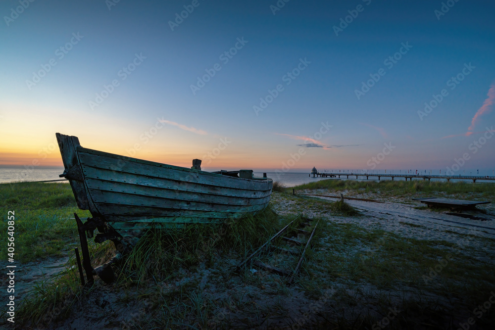 Altes Boot an Land in der Abenddämmerung auf Deich mit Blick auf das Meer 
