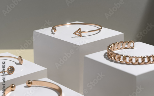 Modern golden arrow shape bracelets on white cubes