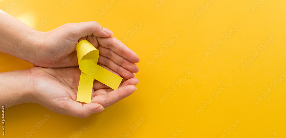 Woman hands with yellow gold ribbons, Sarcoma Awareness. Woman hands with yellow gold ribbons, Sarcoma Awareness.