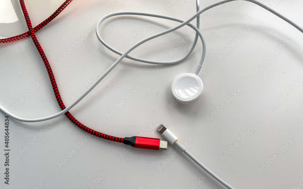 Usb c, watch, and cellphone charging cables on a white table. Usb c, watch, and cellphone charging cables on a white table.
