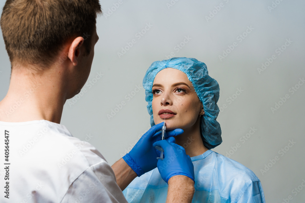 Lips augmentation injections for attractive girl on white background. Plastic surgeon does injection in lip in medical clinic. Cosmetic rejuvenating facial treatment. Empty space for advert Lips augmentation injections for attractive girl on white background. Plastic surgeon does injection in lip in medical clinic. Cosmetic rejuvenating facial treatment. Empty space for advert