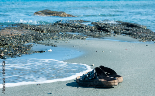 dramatic image of sandals on the beach of the caribbean coast of the dominican republic, with waves and rocks and sand on the beach. 