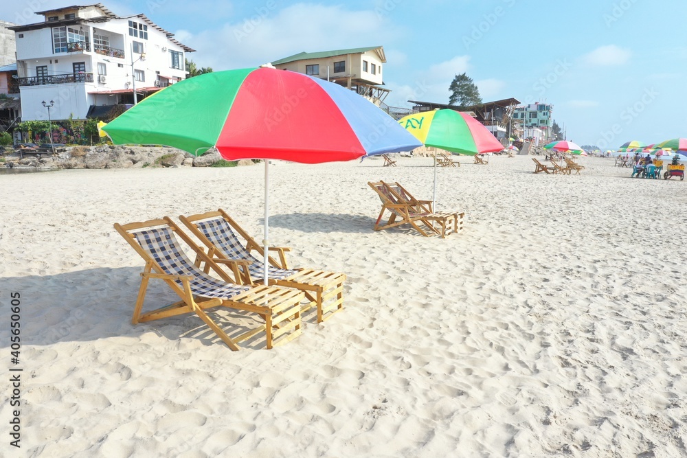 Brightly colored umbrella placed above luxury seats on a tropical beach
