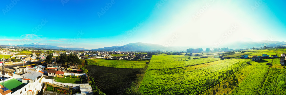 Obraz premium Panoramic aerial over green grasses of many meadows with the mountains in the background