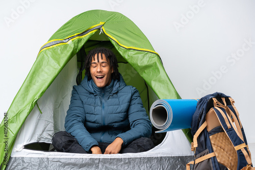 Young african american man inside a camping green tent shouting to the front with mouth wide open