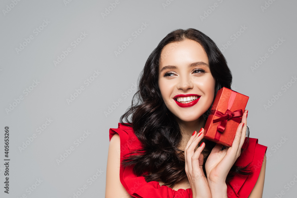 cheerful woman with red lips holding gift box isolated on grey cheerful woman with red lips holding gift box isolated on grey