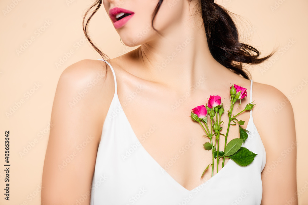 cropped view of surprised young woman near flowers isolated on pink