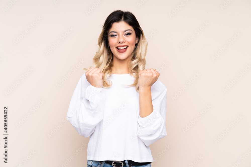 Teenager girl isolated on beige background celebrating a victory in winner position Teenager girl isolated on beige background celebrating a victory in winner position