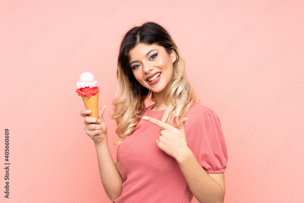 Teenager girl holding a cornet ice cream isolated on pink background and pointing it Teenager girl holding a cornet ice cream isolated on pink background and pointing it