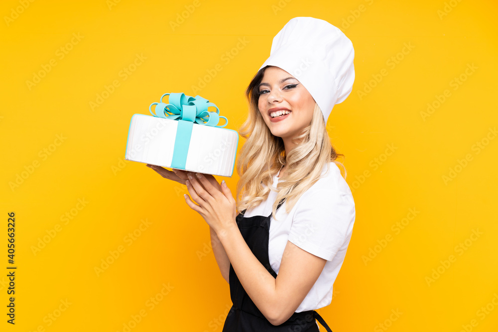 Teenager girl pastry holding a big cake isolated on yellow background Teenager girl pastry holding a big cake isolated on yellow background