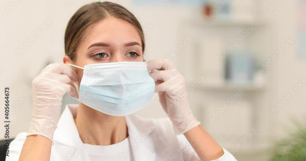 Female doctor putting on medical mask and protective goggles in clinic Female doctor putting on medical mask and protective goggles in clinic