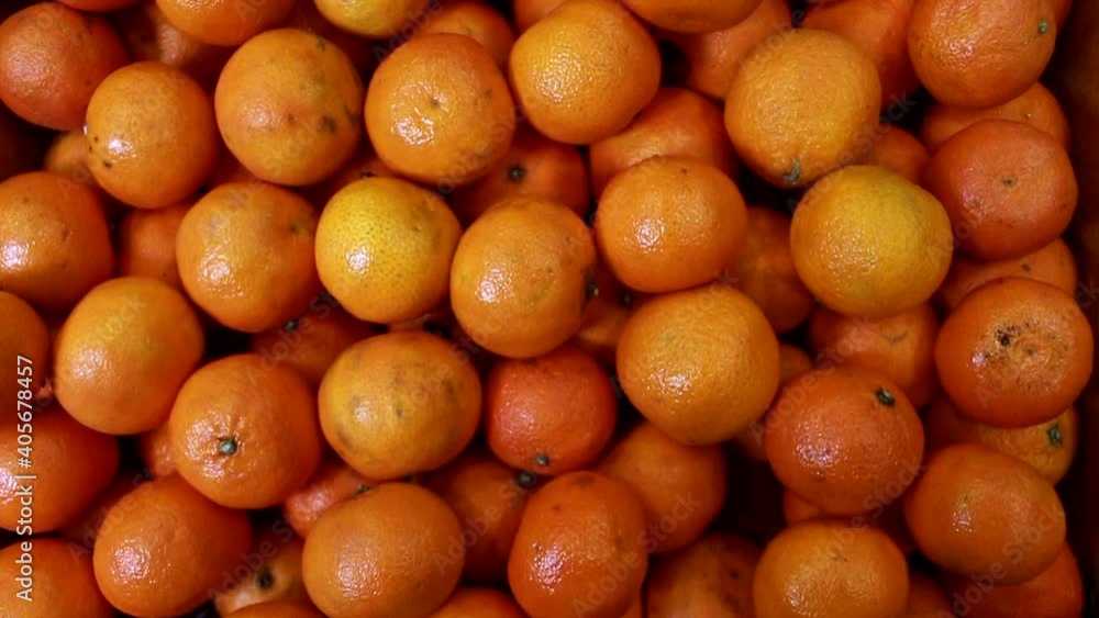 Ripe orange pile of tangerines in a local fruit market. Overhead slide shot of mandarines. Ripe orange pile of tangerines in a local fruit market. Overhead slide shot of mandarines.