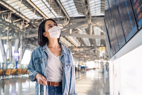 Girl traveler wearing face mask looking at time table to check flight © Kawee