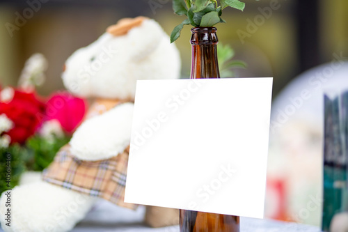 Blank card on the bottle with clipping path. White paper on the table. Empty card valentine concept.