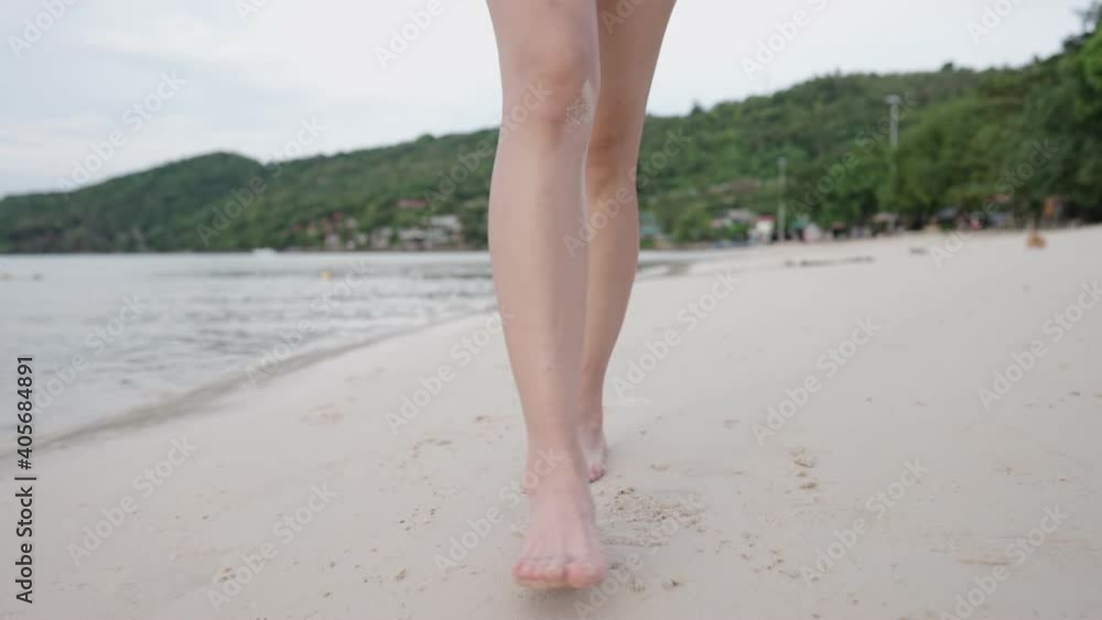 Slow motion, female barefoot walking on clear sand beach, calm waves low tide, tropical island beach, summer vacation travel destinations, escape from it all, freedom lifestyle carefree worry free Slow motion, female barefoot walking on clear sand beach, calm waves low tide, tropical island beach, summer vacation travel destinations, escape from it all, freedom lifestyle carefree worry free