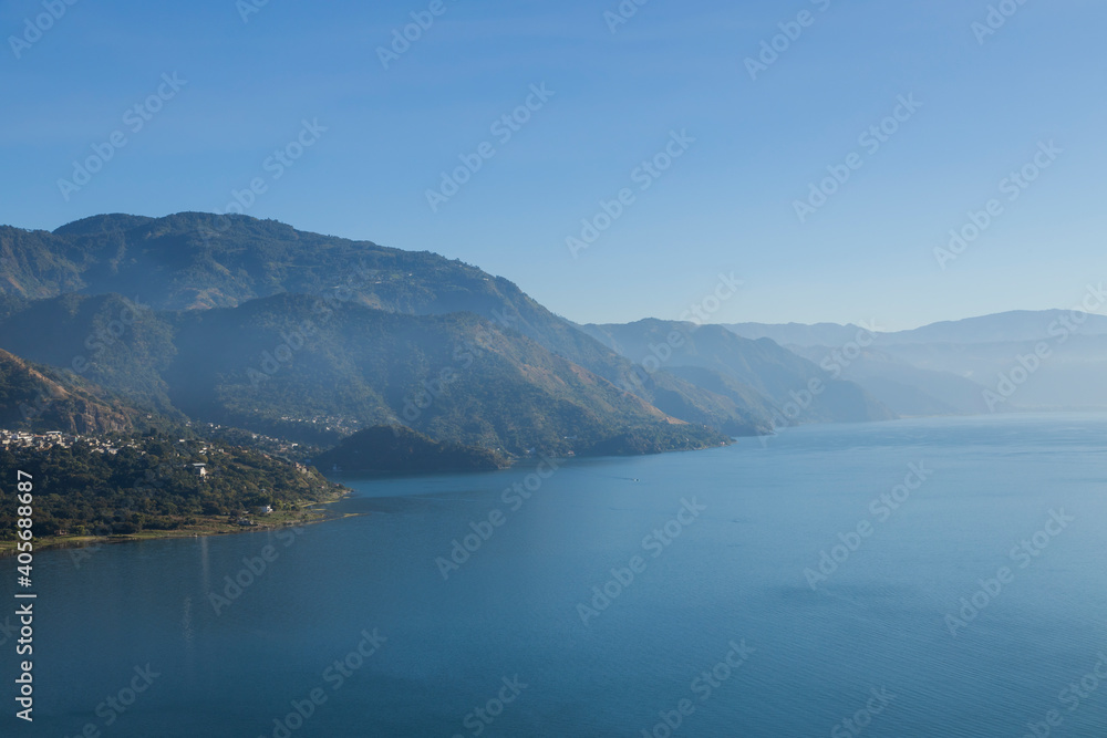 Lake Atitlan in Guatemala in the morning seen from the viewpoint in San Juan la Laguna - landscape of lake surrounded by mountains with sunrise light