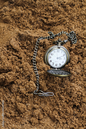 a vintage pocket watch on brown sand