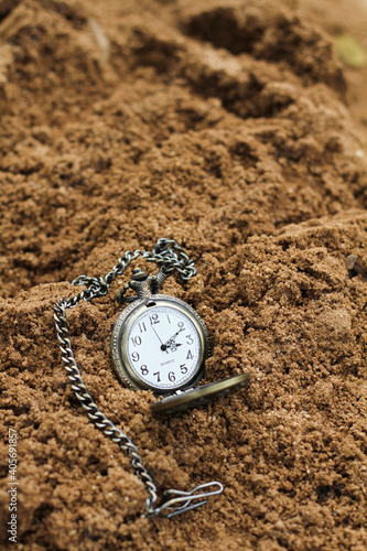 a vintage pocket watch on brown sand